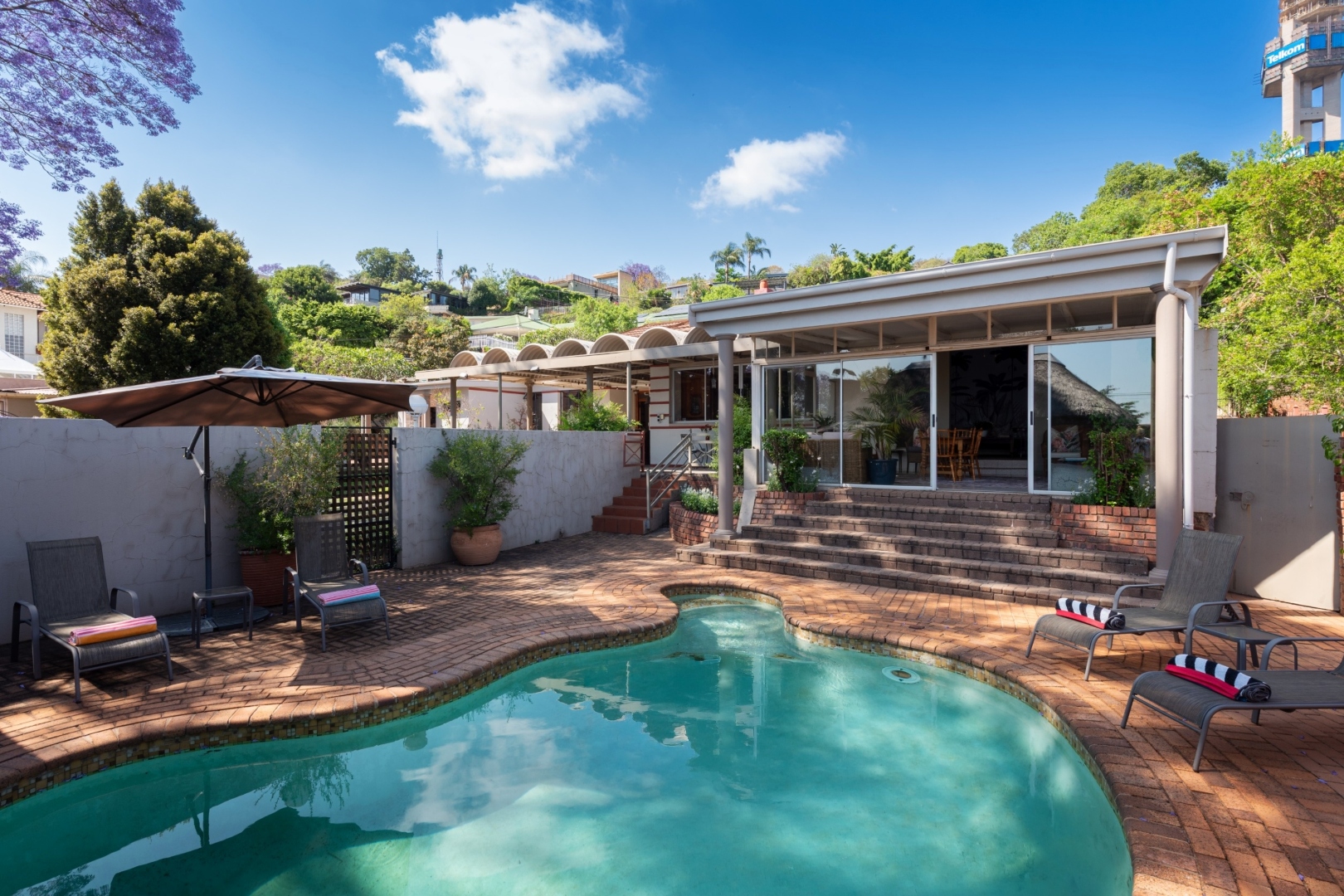 Curved outdoor swimming pool with sun loungers at House Falcon Guest House, Muckleneuk Pretoria